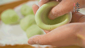 將均分的艾草面團(tuán)搓成圓，挖一個(gè)窩，放入餡心，再搓成圓。