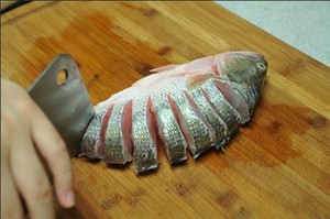 將鱸魚清洗干凈，從脊椎處切斷至腹部，腹部保留1cm左右不要切斷。