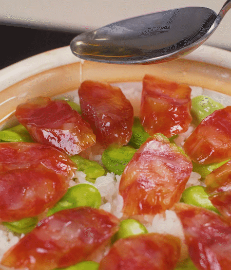 大米出現(xiàn)小孔時(shí)開(kāi)蓋放香腸，往鍋邊淋入少許油，再燜煮8~10分鐘左右。