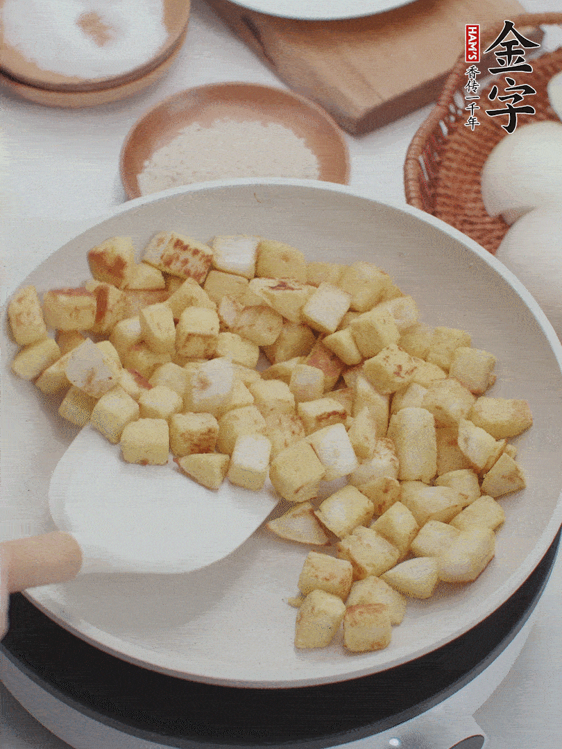 起鍋熱油，倒入饅頭丁，小火煎至蛋液凝固定型再翻面，饅頭丁部煎至金黃時(shí)盛起待用。