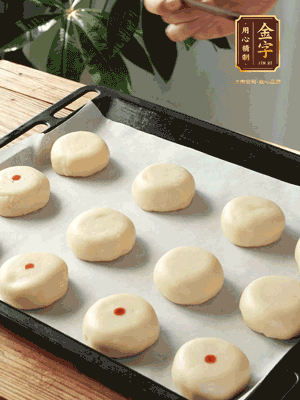 收口向下放在案板上，輕輕將月餅坯按扁，用筷子點(diǎn)紅點(diǎn)做裝飾