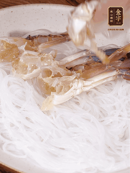 盤(pán)底墊上粉絲，擺上梭子蟹、火腿片，撒姜粒，淋上蒸魚(yú)豉油、花雕酒調(diào)味腌制15分鐘